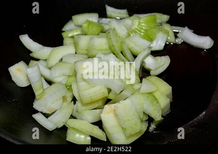 Cipolle tritate grossolanamente, in una padella nera. Girasole o olio di oliva sullo sfondo Foto Stock