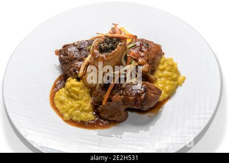 Ossobuco Milanese.Bone hole carne con risotto giallo italiano in bianco piastra isolata su bianco Foto Stock