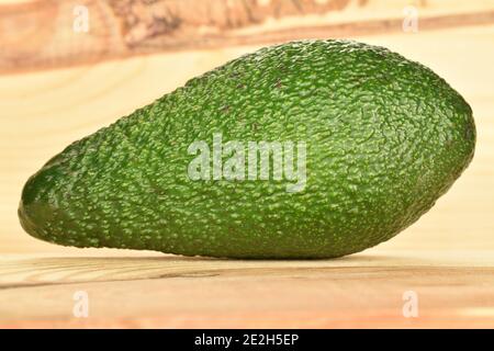 Un delizioso avocado biologico intero verde maturo, su uno sfondo di legno naturale. Foto Stock