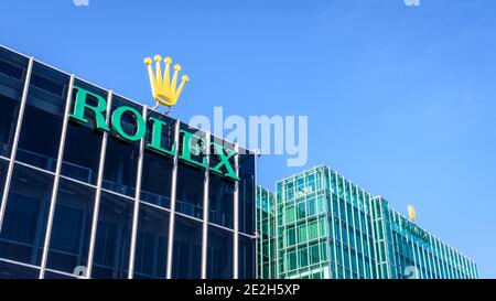 Vista dal basso del logo Rolex nella parte superiore di un edificio presso la sede del marchio svizzero di orologi di lusso a Ginevra. Foto Stock