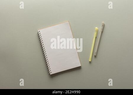 Blocco note a spirale aperto su sfondo grigio , taccuino e penna giacciono su carta textural, concetto di posa piatta in colori trendy dell'anno giallo e grigio Foto Stock