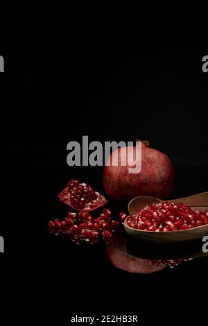Melograno frutta e semi con gocce d'acqua su sfondo riflettente. Foto Stock