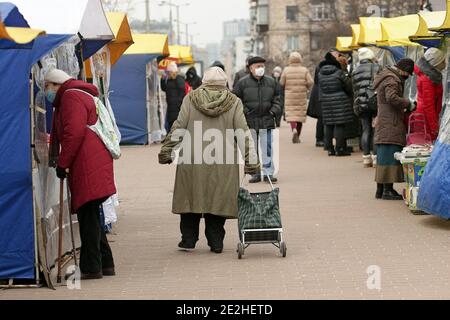 Non esclusivo: KIEV, UCRAINA - 13 GENNAIO 2021 - una donna anziana tira una borsa carrello di shopping in un mercato agricolo durante il blocco del coronavirus, Kiev, ca Foto Stock