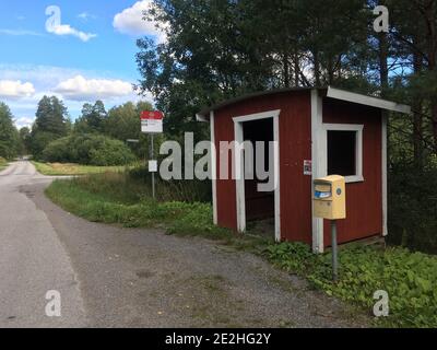 Stoccolma, Svezia - 26 agosto 2020: Fermata dell'autobus nella campagna spopolata della Svezia. Con una scatola posta accanto ad esso e una piccola casa rossa per prendere la baia Foto Stock