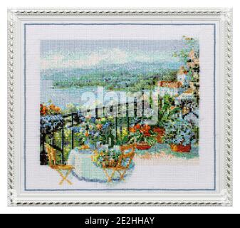 Quadro ricamato in una cornice di apertura, caffè all'aperto terrazza con vista sul mare, punto a croce su tela tessile, isolato su sfondo bianco Foto Stock