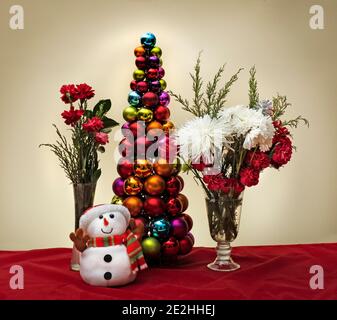 Scena di Natale con fiori pupazzo di neve e albero di natale fatto di decorazioni a sfere decorative lucide Foto Stock