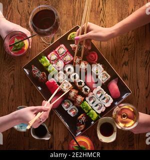 Vista dall'alto. Due ragazze stanno mangiando il sushi. Set di vari tipi di panini e sushi con bevande Foto Stock