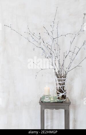 Rami decorativi dipinti in bianco con piccoli ornamenti a forma di stella  e. una candela su una sedia Foto stock - Alamy