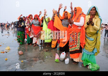 I pellegrini pregano al fiume Gange dopo aver fatto il bagno santo durante Makar sankranti sulla spiaggia, una confluenza del Gange e del mare. Credono che il bagno santo durante Sankranti li condurrà verso il cielo dopo la morte. Foto Stock