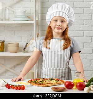 bambina in cappello chef e un grembiule cucina pizza in cucina Foto stock -  Alamy