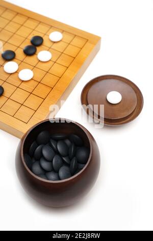 Goban, Baduk, Weiqi o Maklom - gioco da tavolo di strategia asiatica tradizionale. Pietra bianca e nera del gioco da tavolo cinese Foto Stock