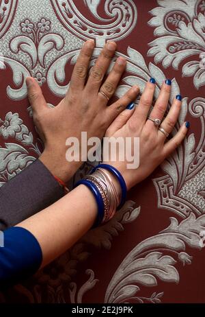 Appena sposato internazionale multirazziale coppia mani con anelli su carta da parati con monogrammi, marito indiano e moglie europea, diverse tonalità della pelle Foto Stock