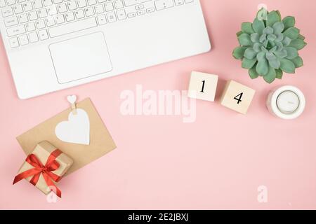 Composizione per San Valentino 14 febbraio. Delicato sfondo rosa, computer portatile e cosmetici. Biglietto d'auguri. Disposizione piatta, vista dall'alto, spazio per la copia. Foto Stock