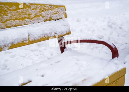 panchine di legno giallo del parco coperte di neve Foto Stock