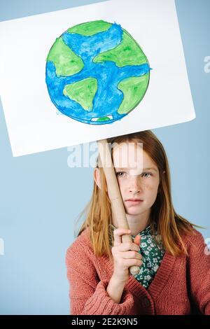 Triste ragazza dai capelli rossi attivista eco con poster verde terra Foto Stock