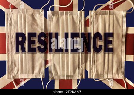 Vista dall'alto di tre maschere sul volto britannico bandiera con la parola resilienza aggiunta alla foto Foto Stock