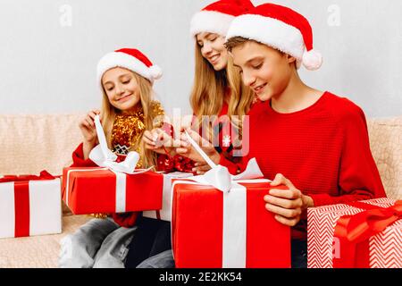 Buon anno e buon Natale! Felice famiglia, una giovane madre e la sua piccola figlia e figlio, indossando cappelli di babbo natale, celebrare il nuovo anno a. Foto Stock