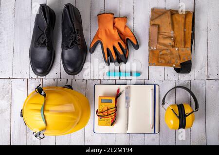 Indumenti da lavoro per un lavoratore di produzione su un tavolo bianco. Accessori per la protezione personale e utensili elettrici utilizzati sul lavoro. Sfondo chiaro. Foto Stock