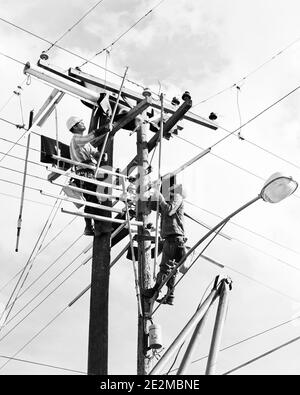 ANNI '60 DUE UOMINI CHE LAVORANO SU CAVI ELETTRICI DI PUBBLICA UTILITÀ A. PARTE SUPERIORE DEI POLI DI ALIMENTAZIONE - I5376 HAR001 MANODOPERA DI PROTEZIONE HARS LINEE DI LAVORO OCCUPAZIONI MANUTENZIONE UTILITY DIPENDENTE LINEMAN STREET LAMP LINEMEN MEDIO-ADULTO UOMO MEDIO-ADULTO GIOVANE UOMO ADULTO NERO E BIANCO CAUCASICO ETNIA HAR001 LAVORARE VECCHIE LINEE ELETTRICHE DI PUBBLICA UTILITÀ Foto Stock