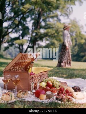 1980 CESTINO PIC-NIC VINO FORMAGGIO FRUTTA PANE MORBIDO FUOCO ANONIMO DONNA IN BACKGROUND - KC8848 DAS001 HARS ESTATE FELICITÀ TEMPO LIBERO UVA PICNIC AL FRESCO GOURMET PICNIC ELEGANTE ANONIMO FUORI FOCALIZZAZIONE PASTICCERIA CAUCASICA ETNIA VECCHIO STILE Foto Stock