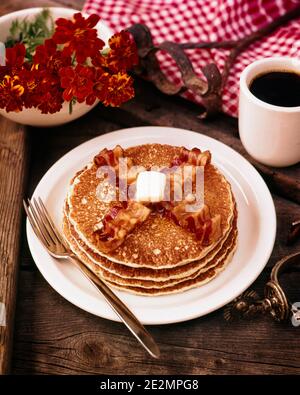 COLAZIONE DEGLI ANNI '70 CON QUATTRO FRITTELLE DI FARINA E DUE STRISCE DI PANCETTA BURRO TAZZA FORTE DI CAFFÈ NERO FIORI STIVALE WESTERN SPERONE - KF4442 HAR001 HARS CONCEPTUAL STILL LIFE ELEGANTE SPERONE MARIGOLDS MARIGOLDS FLAPJACKS GRIDDLE TORTE HAR001 VECCHIO STILE Foto Stock