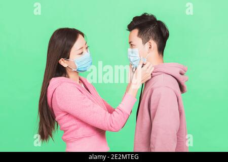 La giovane coppia aiuta a indossare la maschera protettiva per il viso Foto Stock