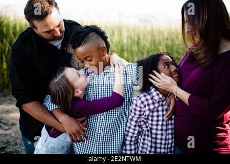 Famiglia di cinque persone che si abbraccia al parco di Chula Vista Foto Stock