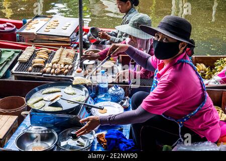 I fornitori Cook e servono cibo di strada dalle loro barche a. Mercato galleggiante Foto Stock