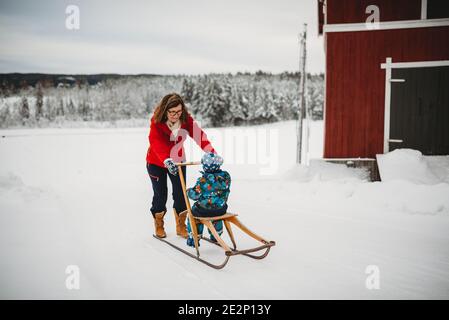 Nonna su vecchia slitta antica con nipote in fattoria in Norvegia Foto Stock