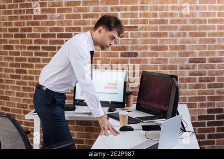 Uomo d'affari focalizzato che controlla le scorte di forex sui computer in ufficio Foto Stock