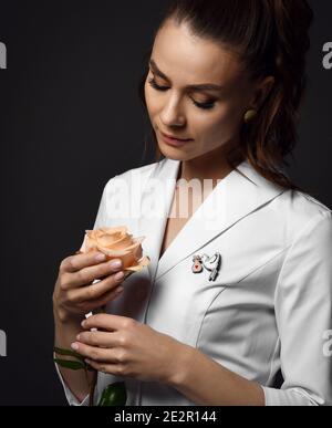 Ritratto di bella donna medico ginecologa o infermiera in bianco abito medico uniforme stand che tengono rosa in mani Foto Stock