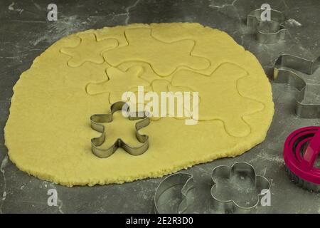 Pasta sfoglia sul tavolo. L'impasto grezzo viene arrotolato su una superficie di lavoro infarinata con un perno di laminazione in legno Foto Stock