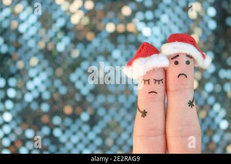 L'arte delle dita di una coppia dispiaciuta celebra il Natale. Concetto di uomo triste e donna nei cappelli di nuovo anno. Foto Stock