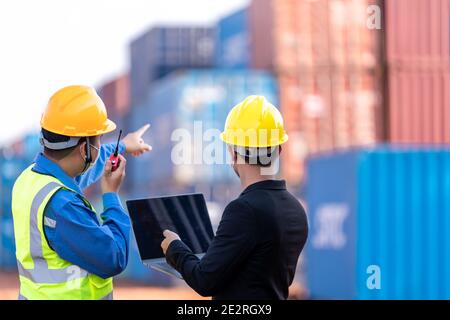 Lavoro di squadra, caposquadra di magazzino logistico maschile asiatico con lavoratore che utilizza il laptop che controlla la pianificazione elenco e la strategia di contenitori scatole da carico shi merci Foto Stock