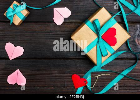 Una romantica confezione regalo avvolta in carta artigianale e legata con un nastro. Un regalo per una persona cara. Nota romantica a forma di cuore. Foto Stock