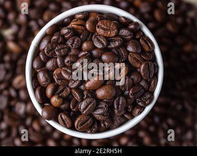 Tazzina di riciclo del caffè da asporto con chicchi di caffè tostati sullo sfondo dei chicchi di caffè. Vista dall'alto. Primo piano. Messa a fuoco selettiva. Foto Stock