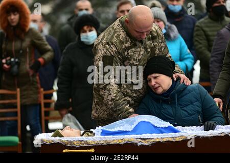 Non esclusivo: ZAPORIZHZHIA, UCRAINA - 14 GENNAIO 2021 - la madre e un fratello maggiore del soldato perito Oleh Andrienko grieve durante la funera Foto Stock