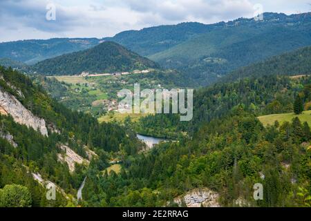 Bella aqua e colori blu del lago Spajici e il fiume Beli Rzav, sulla montagna di Tara Verde, alberi e piccole case di villaggio e dam. Foto Stock