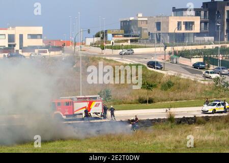 Vigili del fuoco e polizia in presenza e di mettere fuori una strada Fuoco d'erba in un giorno soleggiato di ottobre Santander Cantabria Spagna Foto Stock