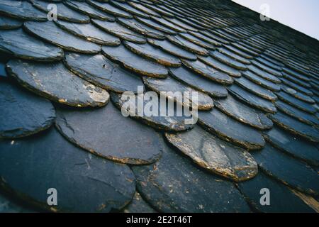 tetto con vecchie piastrelle di colore scuro, tra nero e grigio. Creare una ripetizione con texture da una prospettiva angolata Foto Stock
