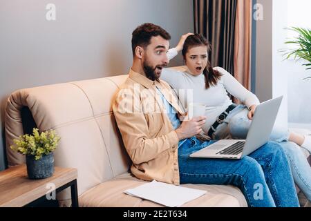 Basta guardarlo. Un uomo bello in camicia arancione e jeans blu e attraente giovane donna in dolcevita bianco insieme ha visto qualcosa di scioccante Foto Stock