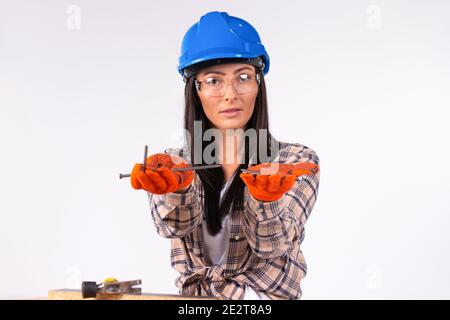 Donne carine in un casco e occhiali in posa con unghie nelle loro mani su uno sfondo bianco. Foto Stock