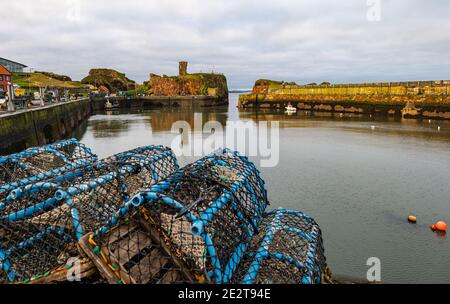 Dunbar Harbour, East Lothian, Scozia, Regno Unito, 15 gennaio 2021. Industria della pesca: Il porto di Victoria, il porto principale della città, è vuoto con una barca da pesca solitaria. Le pentole di aragosta fiancheggiano la banchina con il castello di Dunbar in rovina sullo sfondo Foto Stock