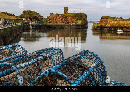 Dunbar Harbour, East Lothian, Scozia, Regno Unito, 15 gennaio 2021. Industria della pesca: Il porto di Victoria, il porto principale della città, è vuoto con una barca da pesca solitaria. Le pentole di aragosta fiancheggiano la banchina con il castello di Dunbar in rovina sullo sfondo Foto Stock