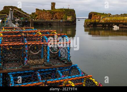 Dunbar Harbour, East Lothian, Scozia, Regno Unito, 15 gennaio 2021. Industria della pesca: Victoria Harbour, il porto principale della città, è vuoto con pentole di aragosta sulla banchina e rovinato Dunbar Castle sullo sfondo Foto Stock