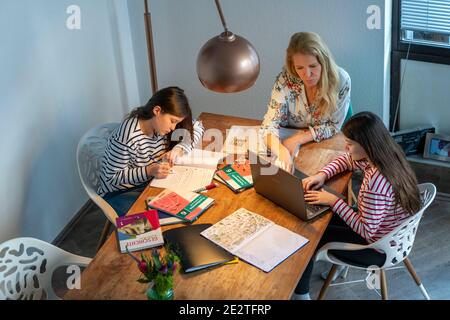 Homeschooling, durante il blocco nel gennaio 2021, madre aiuta le sue due figlie, a casa, ad imparare, con libri di testo e computer, la chiusura della scuola, Foto Stock