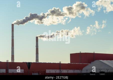Tubi con enormi nuvole di fumo nella fabbrica primo piano contro il cielo blu in una giornata di sole. Concetto di ecologia, inquinamento ambientale Foto Stock