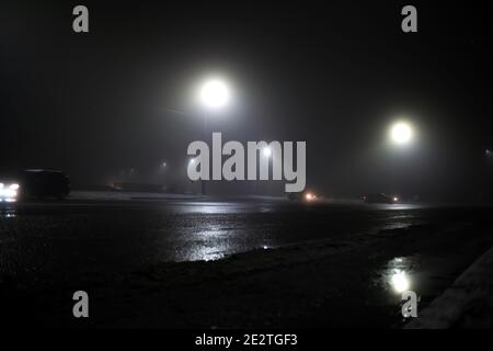 Auto in un incrocio non regolamentato in nebbia di notte, cattive condizioni meteorologiche per la guida Foto Stock