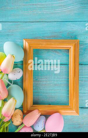 Primavera e Pasqua sfondo vacanze con fiori di tulipano, colorate uova pastello su tavolo blu vista dall'alto. Buon biglietto d'auguri pasquale. Foto Stock