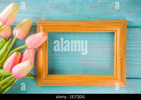 Primavera e Pasqua sfondo vacanze con fiori di tulipano, colorate uova pastello su tavolo blu vista dall'alto. Buon biglietto d'auguri pasquale. Foto Stock